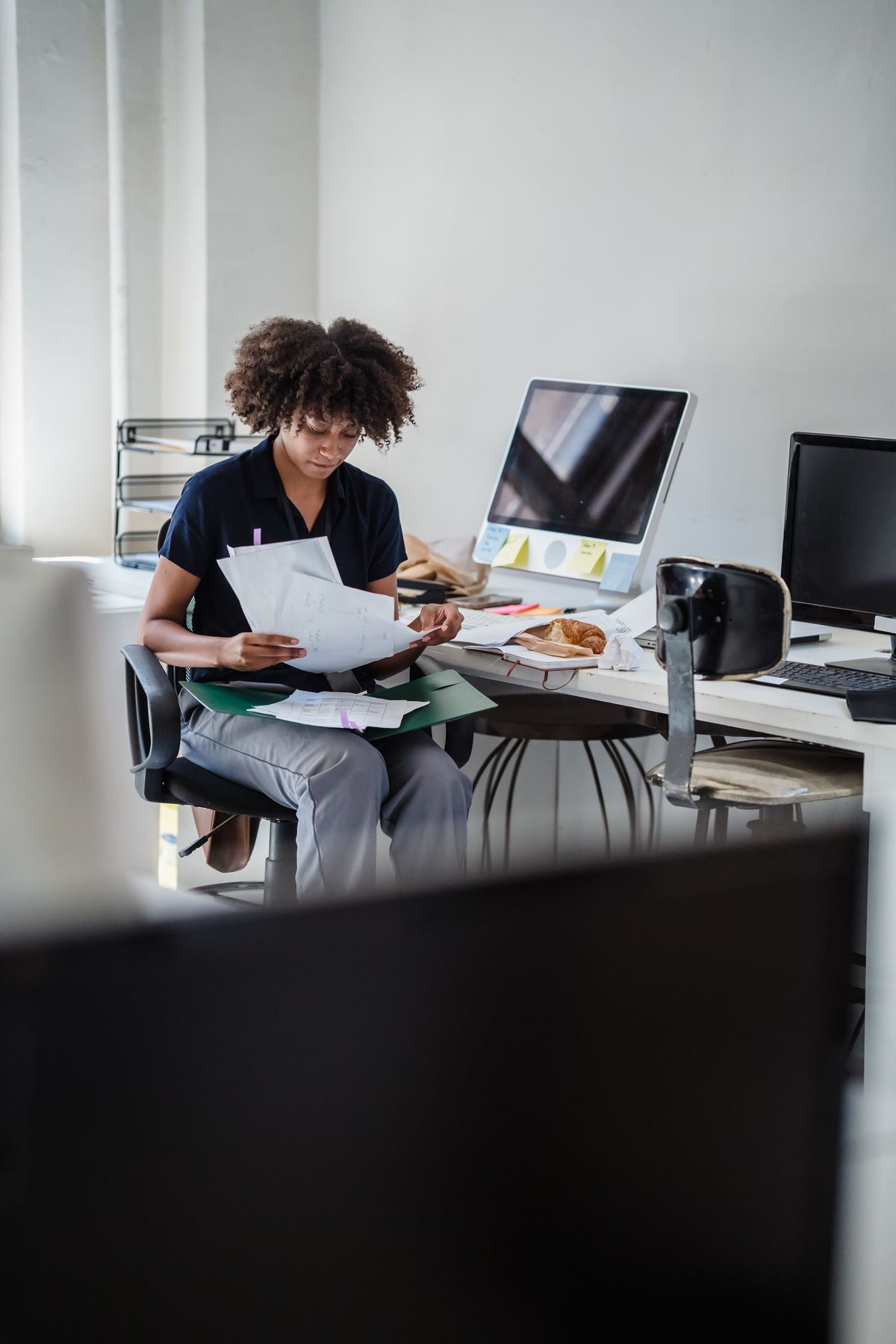 Une professionnelle examine des documents devant son ordinateur